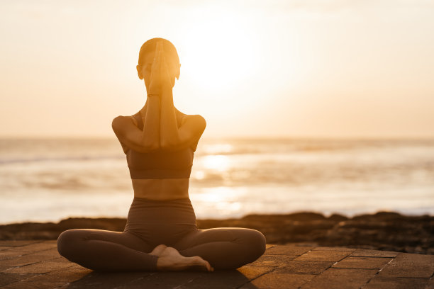 日落时在海滩上做瑜伽。在海里做体式，享受生活的女人图片下载