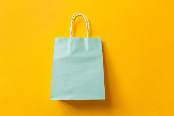 简单的最小设计购物袋孤立在橙色的背景。网上或购物中心购物狂概念。黑色星期五圣诞季大减价。平铺顶视图复制空间，模拟图片下载