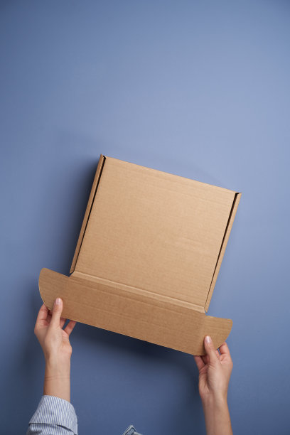 女人双手打开空纸板箱，俯视图图片下载