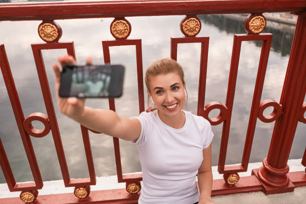 年轻漂亮的女运动员在街上休息的时候用手机图片下载