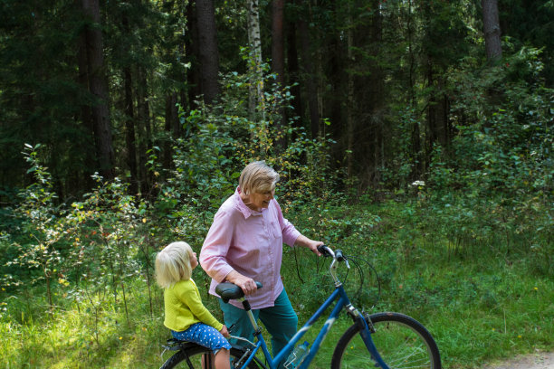 奶奶和小孙女在大自然中骑自行车图片下载