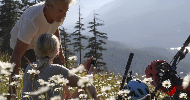 一对夫妇骑着山地电动自行车在高山草地的野花中放松图片下载