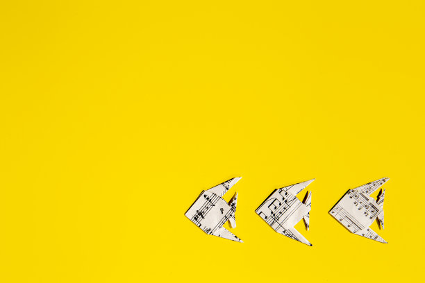 在黄色背景上的折纸鱼的学校。图片下载