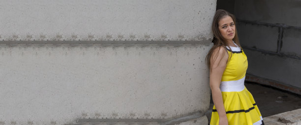 年轻美丽的女孩在一个漂亮的建筑背景黄裙子图片下载