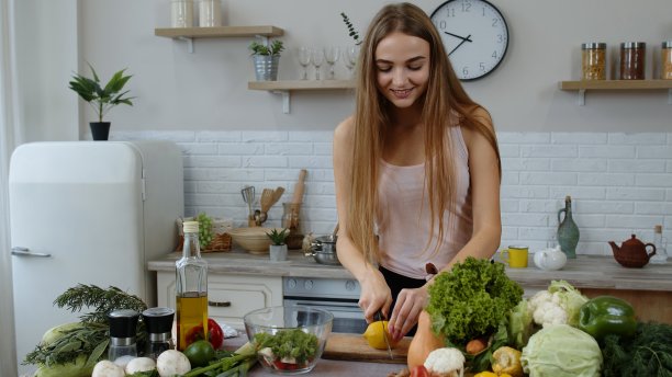 女孩带着多汁的柠檬走进厨房。年轻女子微笑着用刀切新鲜水果图片下载