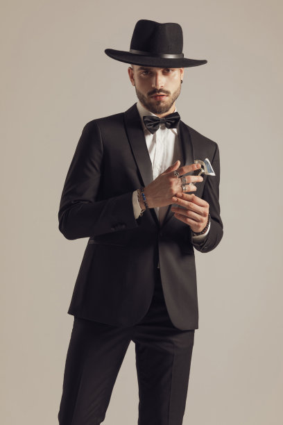 英俊的新郎正在调整他的戒指，戴着帽子和燕尾服图片下载