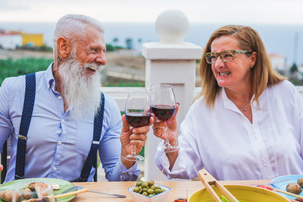 快乐的老年夫妇在户外晚餐时用红酒欢呼-专注于双手图片下载