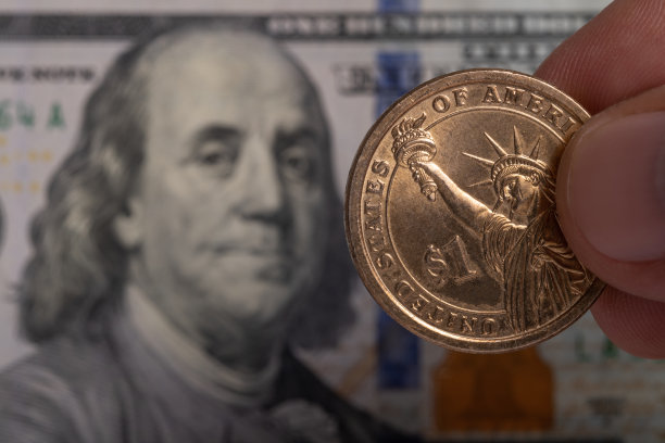 一美元硬币上的100美元纸币的背景。图片下载
