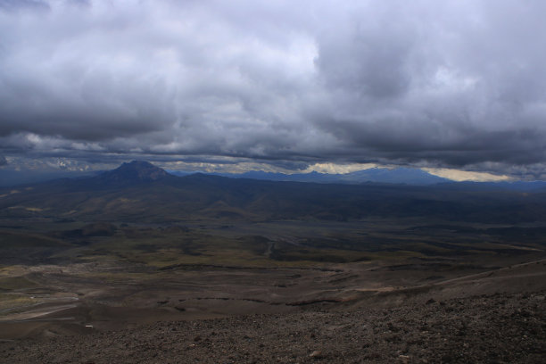 这是一架无人机在一个暴风雨的日子里拍摄的，显示了一堆深灰色和黑色的云在山丘和山谷上空，背景是山脉图片下载