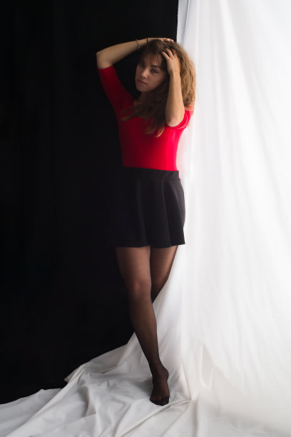 年轻女子触摸她诱人的头发站在白色和黑色的背景图片下载