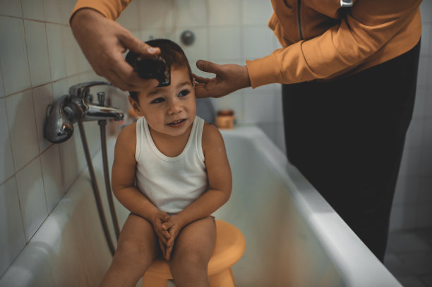 2020年大流行封锁期间，父亲在家给儿子剪头发。Covid-19社会距离图片下载