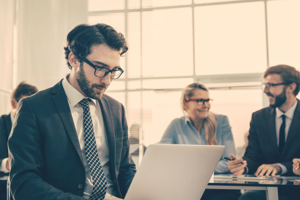 一个自信的商人在办公桌旁用笔记本电脑工作图片下载