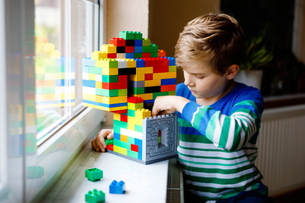 小男孩在玩五颜六色的塑料积木。可爱的学校孩子与建筑和创造建筑的窗户的乐趣。创意休闲技术和机器人在电晕时间图片下载