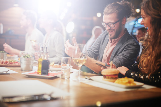 这对可爱的夫妇坐在餐厅里，对着他们在手机上看的视频片段大笑。图片下载