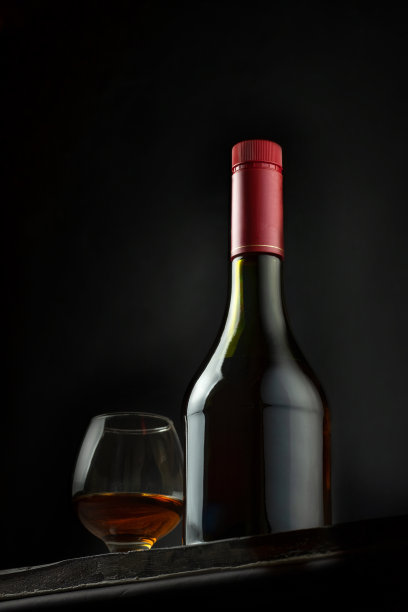 木制背景上的一瓶和一杯白兰地。图片下载