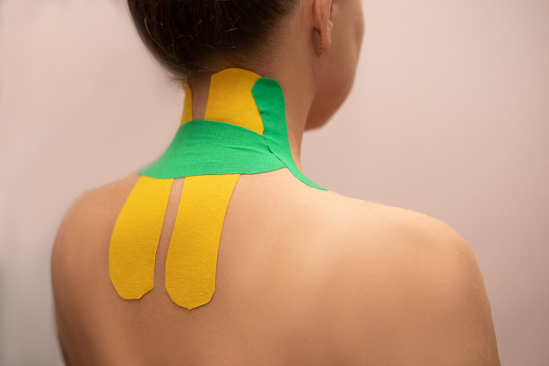 一个年轻的女人与一个明亮的运动疗法胶带与肩膀和背部在治疗师的按摩沙龙或诊所近距离照片。背痛。特写照片图片下载