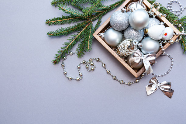 灰色背景下的木制盒子里装着银色的圣诞球和珠子。用冷杉枝作新年或圣诞节的作文图片下载