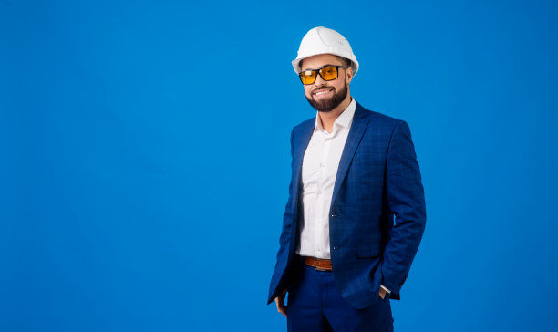 一名年轻的专业人员，戴着安全帽，拿着一个蓝色背景的剪贴板图片下载