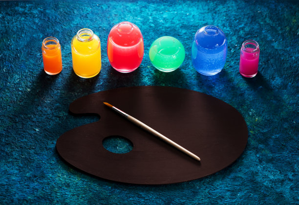 玻璃瓶中的水彩颜料和画家的调色板。图片下载