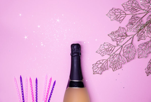 庆典背景为金色的香槟瓶、五彩缤纷的星星、蜡烛和金色的树叶。生日，婚礼或新年的概念。图片下载