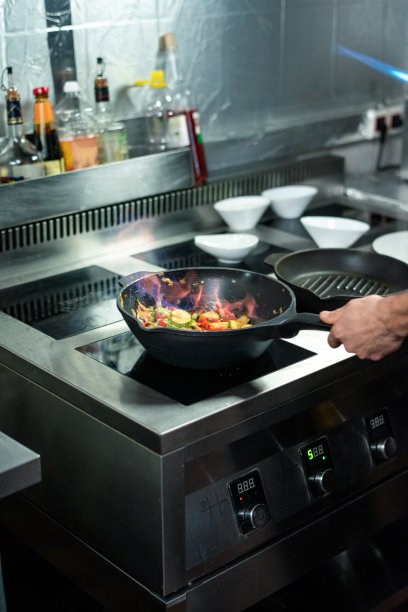 年轻的厨师手持平底锅倒入切碎的蔬菜图片下载