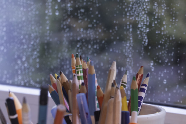 雨天，彩色铅笔放在窗前的书桌上图片下载