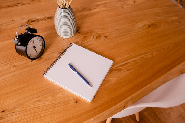 木桌上放着黑色的闹钟、记事本和文具。期限与教育理念。顶部横向查看拷贝空间图片下载