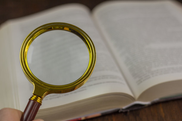 打开书，手里拿着放大镜。图片下载