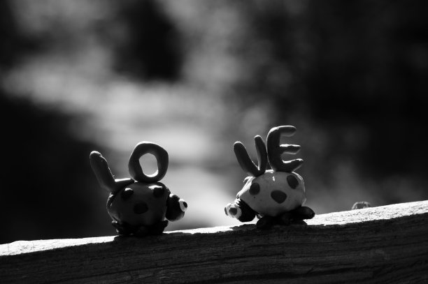 两个橡皮泥做的瓢虫在彩色的背景。在它旁边刻有“爱”的字样。图片下载