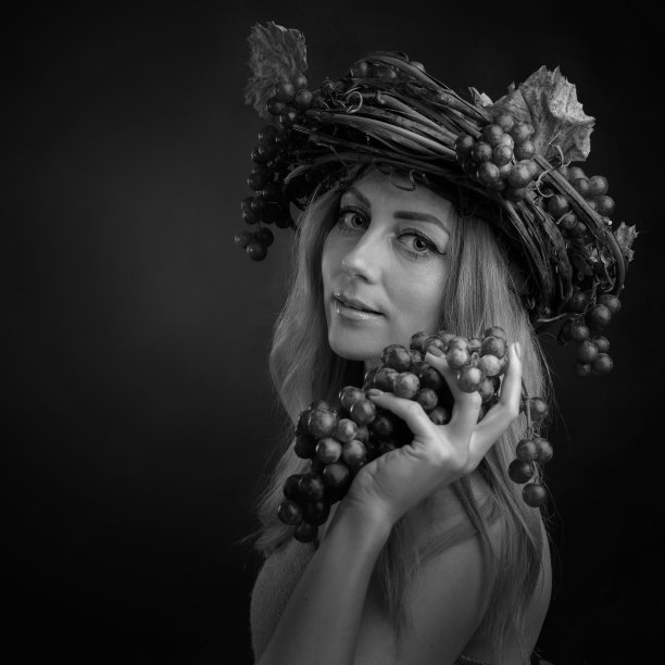 美丽的白种金发女人拿着葡萄的肖像。图片下载