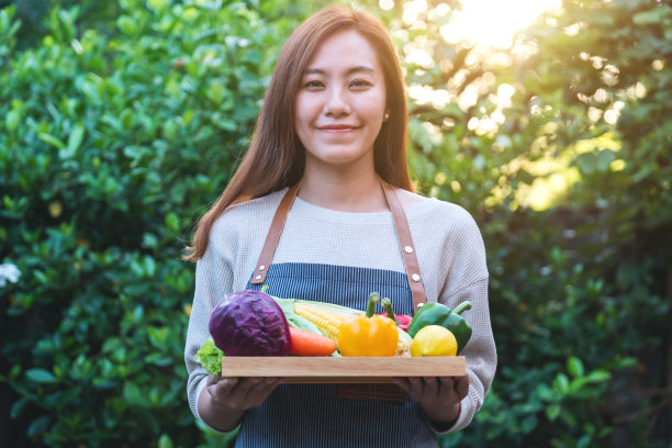 一个女人用木托盘端着一盘新鲜的混合蔬菜图片下载