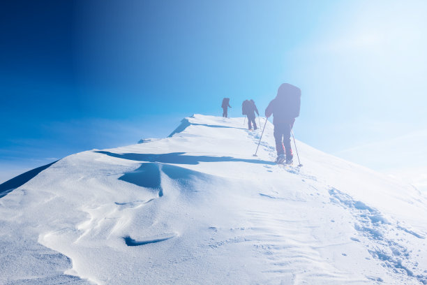 一群徒步旅行者在冬天被雪封住的群山中行走图片下载