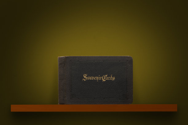 古色古香的卡片相册封面放在木架子上，背靠深棕色的墙壁图片下载