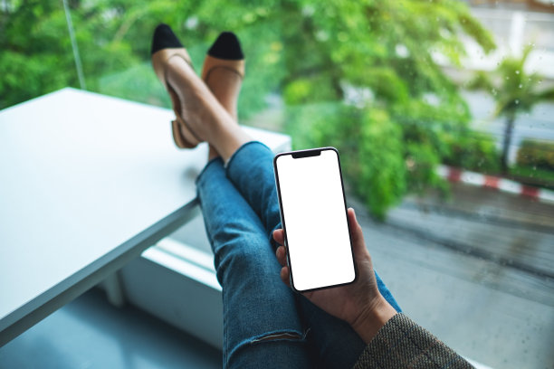 一位女士坐在办公室里，手里拿着手机，手机的桌面屏幕是空白的图片下载