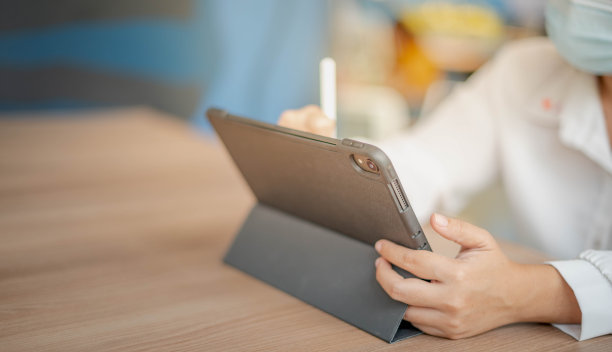 戴着面具用铅笔在Ipad上画画的女人图片下载