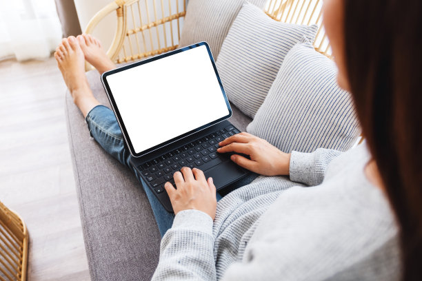 坐在家里沙发上的一名女性在黑色平板电脑上打字，桌面是空白的，白色屏幕就像电脑一样图片下载