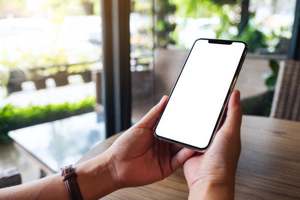 一个女人拿着手机和空白的白色桌面屏幕图片下载