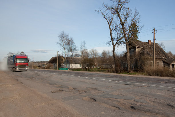 路面坑坑洼洼，背景是卡车，乡村。洞沥青。坑，不安全，坑路。运输图片下载