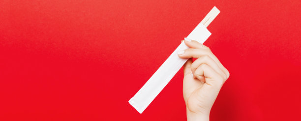 女人的手拿着筷子在一个包在红色的背景。中国菜的概念与空间为您设计图片下载