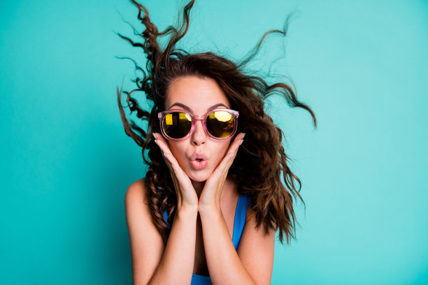 惊讶惊讶无语的照片时髦的女士模特手掌脸粉红色眼镜爆炸刘海发型疯狂的新闻折扣低价季节性销售穿蓝色泳衣孤立的蓝绿色背景图片下载