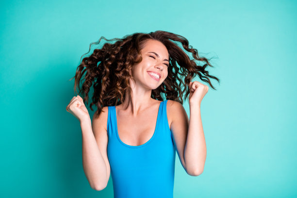 兴高采烈的女孩庆祝泳池派对比赛的照片赢得闭上眼睛举起拳头穿蓝色的紧身衣孤立在蓝绿色的背景图片下载