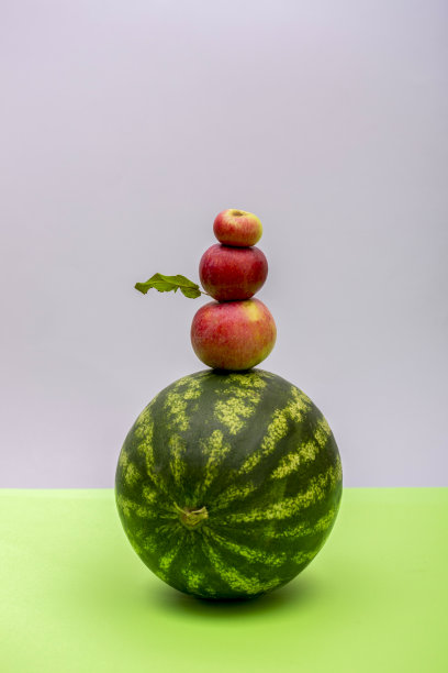 成熟的西瓜和三个苹果在彩色的背景上图片下载
