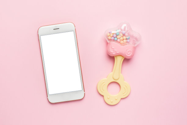 粉色背景上的手机和婴儿玩具图片下载
