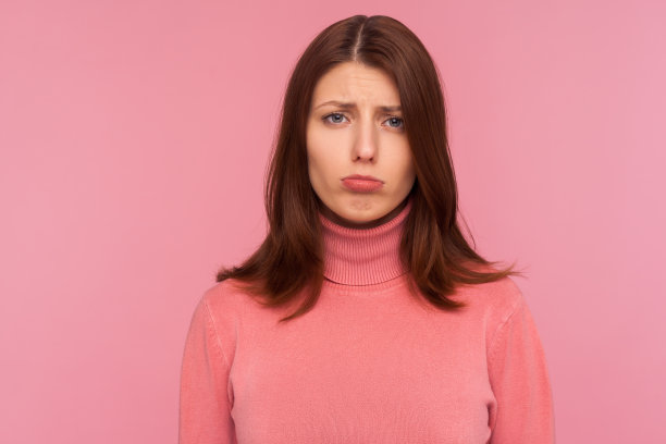 特写肖像深深地沮丧沮丧的黑发女人在粉红色的毛衣看着相机，失望图片下载