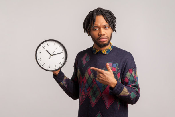 焦虑的不高兴的人与发辫和胡子指着手指在他的手挂钟。我需要更多的时间图片下载