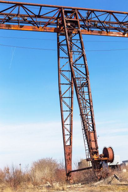 旧的，生锈的门式起重机在铁路上，一个废弃的混凝土工厂。危机、经济崩溃和生产能力的关闭导致了崩溃。全球灾难。一张古老照片的效果。图片下载