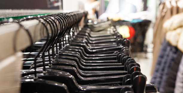 现代时尚女装挂在一家服装店的黑色塑料衣架上。网上购物休闲服装。有选择性的重点图片下载