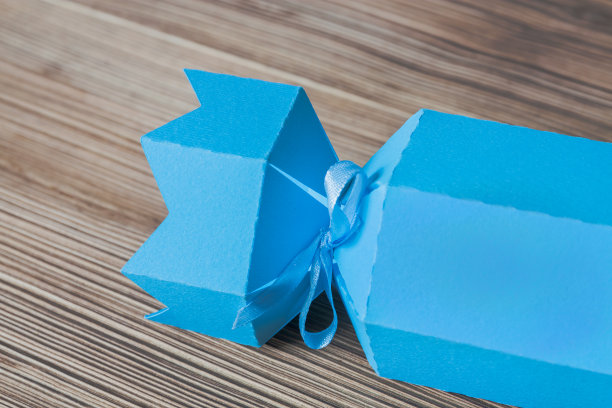 一种圣诞或节日用的蓝色礼物盒，以糖果的形式，由彩色纸板制成，以木制为背景。有选择性的重点图片下载