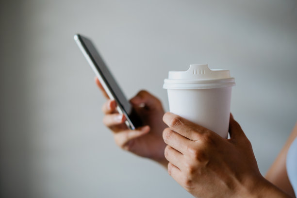 一个正在喝咖啡和使用智能手机的亚洲中国女人素材图片