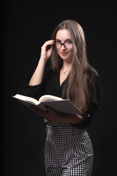 美丽的女人戴着眼镜和书在黑色的背景图片下载